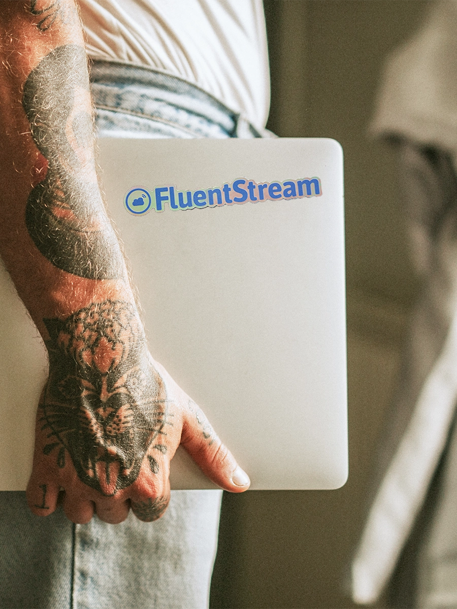 Arm holding closed laptop by their side, FluentStream decal visible on laptop